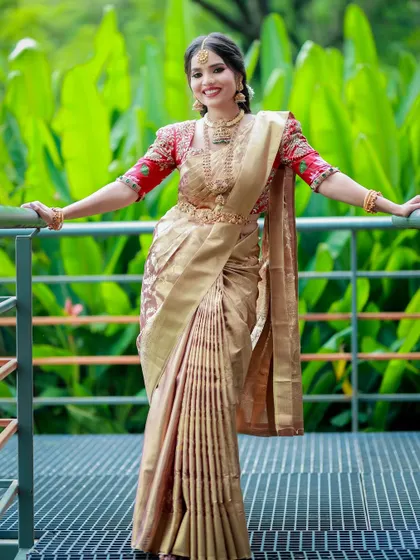 A happy bride in a golden Kanchivaram saree. The pre-pleated drape ensures a perfect look, allowing her to smile and enjoy her day without any fuss.