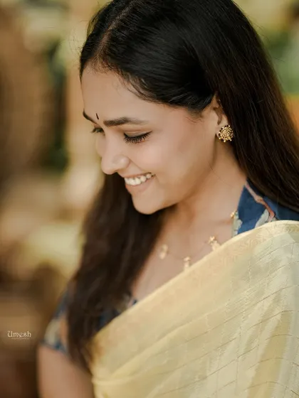 A beautiful close-up shot showing the delicate texture of the yellow saree and the intricate work on the custom blouse. Her happy smile says it all.