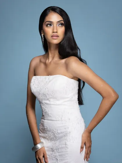 A three-quarter shot of a model in a white bridal gown, with a classic and elegant pose.