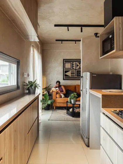 We turned the passage leading to the bedroom into a functional galley kitchen. This strategic layout decision frees up valuable area in the main living space, creating a more open and expansive feel throughout the apartment while keeping the kitchen easily accessible.
