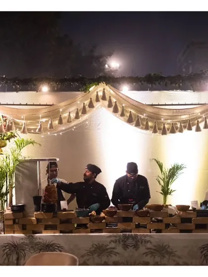A wide view of our chefs at an outdoor live station, set against a beautifully draped backdrop with tassel details.