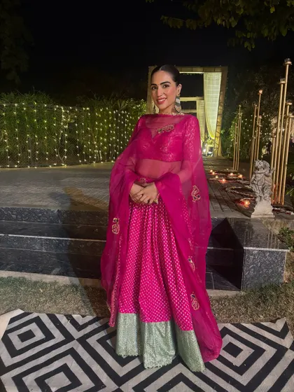 A vibrant pink and green lehenga from House of Masaba, perfect for a mehendi or sangeet. The outdoor setting with fairy lights shows how this outfit comes alive at night.