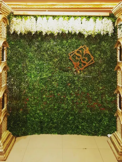 A mantap with ornate pillars and a green foliage backdrop, personalized with a couple's monogram for their baby shower.