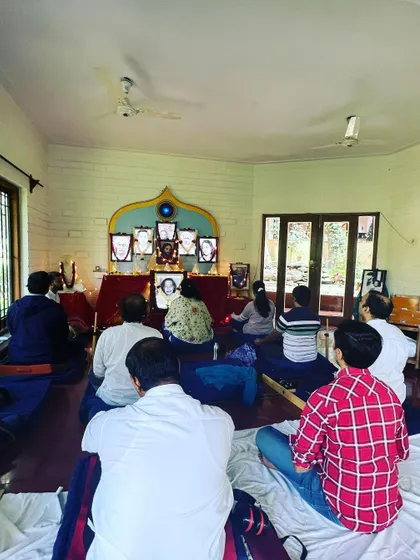 A Christmas meditation in progress, with devotees sitting on meditation cushions and using arm rests for support. We provide a comfortable and supportive environment for everyone to experience the benefits of meditation.