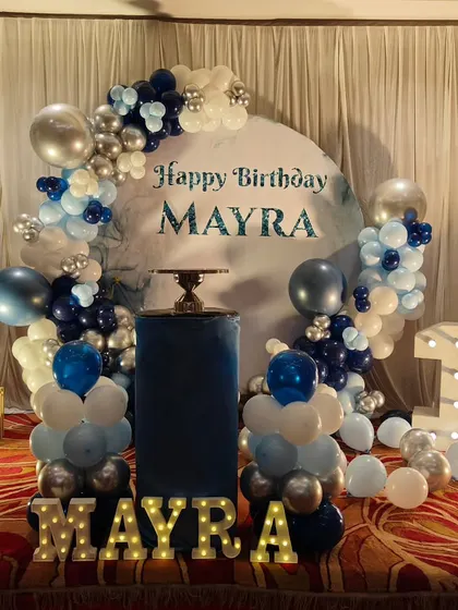 A chic and stylish setup for a 10th birthday. I used a cool palette of navy blue, silver, and white for the balloon garland around a circular backdrop, complemented by large marquee numbers and letters.