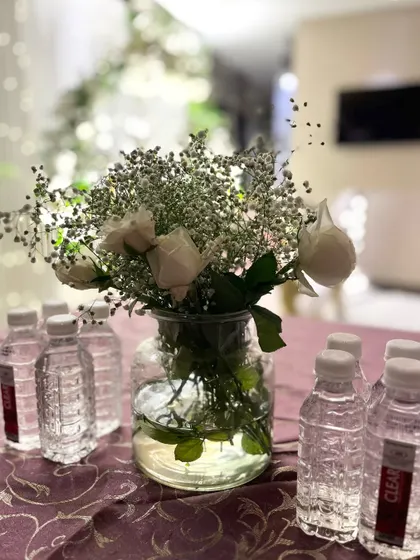 A simple and elegant centerpiece with white roses and baby's breath in a clear glass jar, perfect for an intimate and understated look.