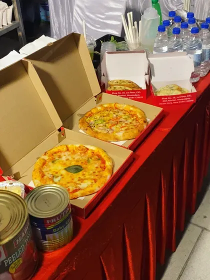 Pizzas ready to be served at an evening event. We offer both classic Margherita and vegetable-loaded options, boxed up and ready for guests to enjoy.