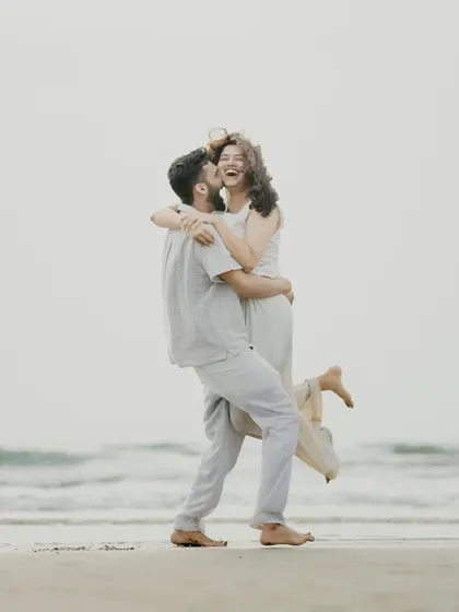 A moment of pure joy captured on a Goa beach. The groom-to-be lifts his partner in a happy embrace, creating a perfect candid shot full of laughter and love.