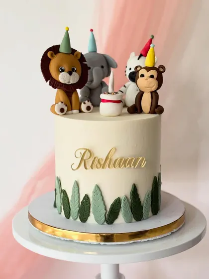 A party in the jungle for Rishaan's first birthday. This cake features a lion, elephant, zebra, and monkey, all wearing tiny party hats.