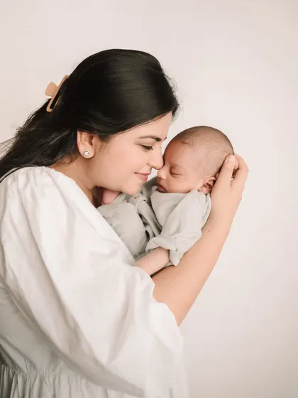 A mother's gentle touch as she holds her sleeping baby close, a timeless and emotional portrait.