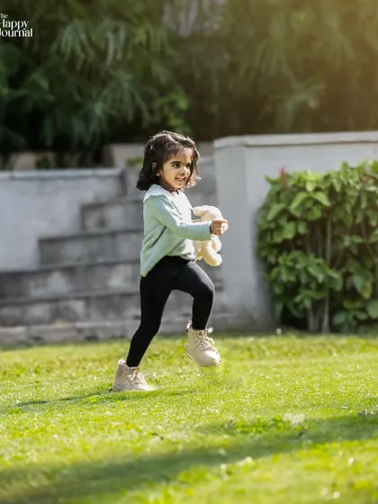 A little girl runs happily across the grass, her best teddy bear friend in hand. A perfect candid shot from an outdoor lifestyle session.