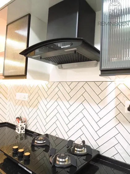This close-up focuses on the black hob set against the white herringbone backsplash. The fluted glass cabinet doors add texture and visual interest while partially obscuring the contents for a tidy look.