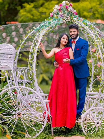A full-length view of the couple with the Cinderella carriage, showcasing the beautiful details of the setup and their coordinated outfits.