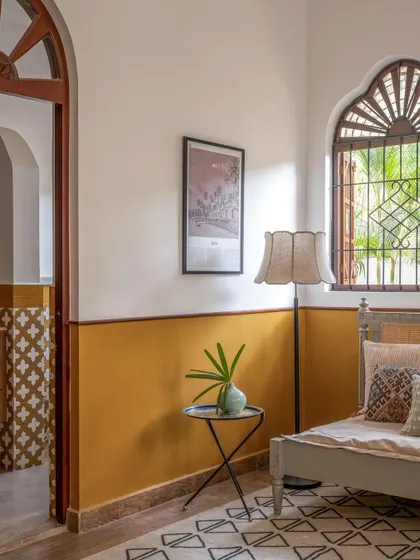 A bedroom from 2023 with a half-painted mustard wall and a view into a bathroom with patterned tiles, showcasing our love for color and pattern.