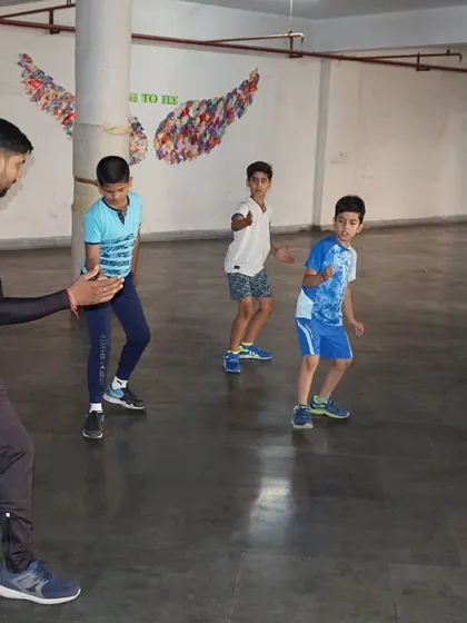 A coach guides a group of young boys through basic footwork patterns. Clear instruction is key to building a solid foundation.