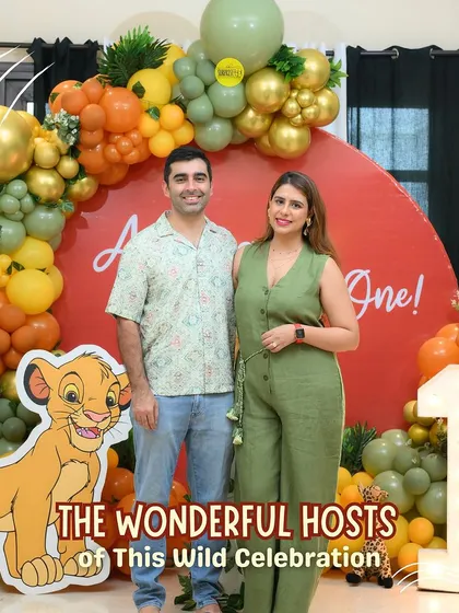 The wonderful hosts of this wild celebration! The proud parents stand in front of the jungle-themed backdrop, ready to celebrate their son's first birthday.