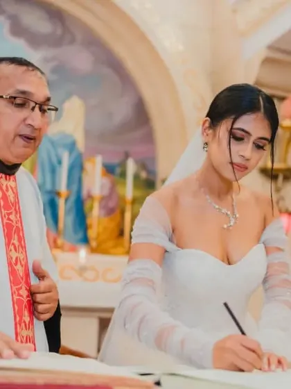 The bride signing the wedding register, officially marking the beginning of her married life, with the church's beautiful art in the background.