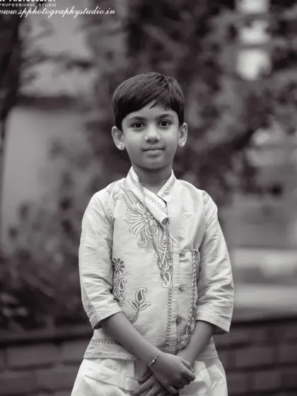 A classic black and white portrait of a young boy in traditional wear. This timeless style emphasizes his expression and the details of his outfit.