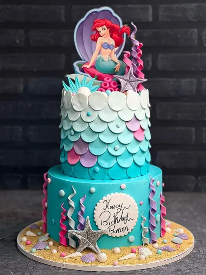 A beautiful Little Mermaid cake! This two tier design features Ariel in her shell, with gorgeous ombre scales and underwater details. A perfect cake for a mermaid themed party.
