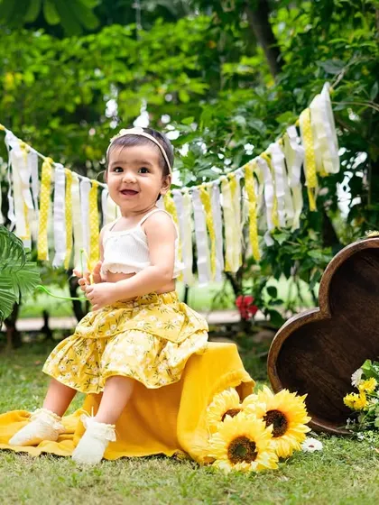 A sunny first birthday in a field of sunflowers. This outdoor setup is perfect for a nature-loving family, creating bright and cheerful portraits.