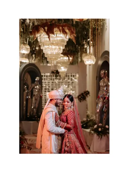 A beautiful portrait of the couple under a grand chandelier, surrounded by opulent decor, capturing the luxury of their wedding.