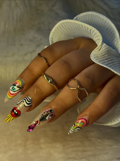 This set is pure art. We created these extra-long stiletto nails with a variety of bold, graphic designs including a rainbow eye, abstract swirls, and heavy rhinestone embellishments.