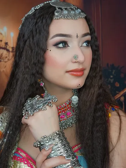 The side profile highlights the crimped hairstyle and the detailed jewelry, which are key elements of this traditional garba look.