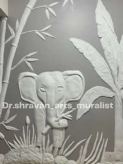 A cute baby elephant sculpted in relief, surrounded by bamboo and banana leaves. This type of work is perfect for adding a touch of playful nature to a room, and the all-white finish keeps it elegant.