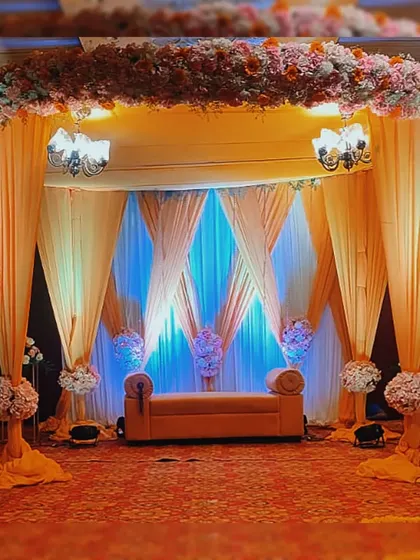 An elegant stage setup for a Haldi ceremony. The combination of warm yellow and cool blue draping, accented with floral arrangements and soft lighting, creates a sophisticated and inviting space.