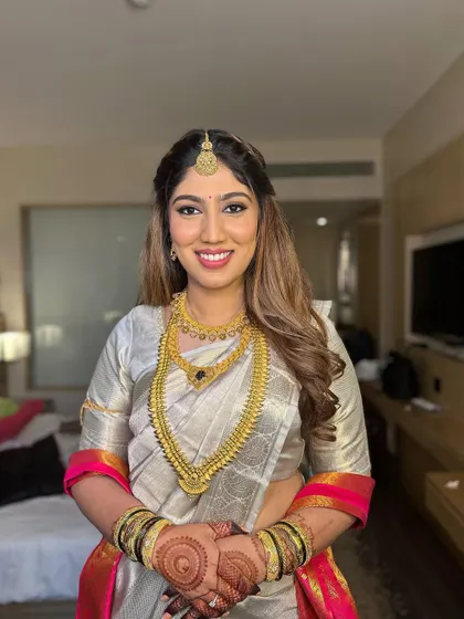 A modern South Indian bridal look featuring a braided half-updo with soft curls and fresh flowers. It's a beautiful fusion of traditional and contemporary styles.