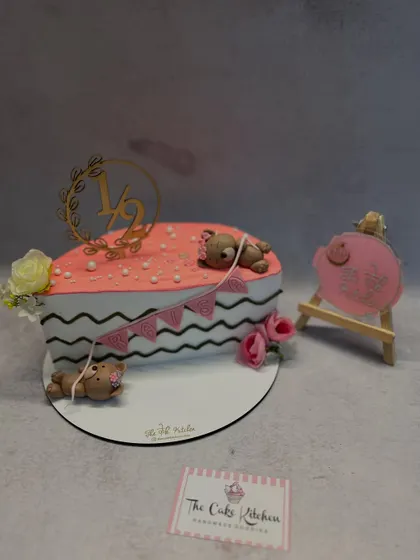 Celebrating the six-month milestone with a half-birthday cake. This heart-shaped cake is decorated with cute sleeping teddy bears and a "1/2" topper.