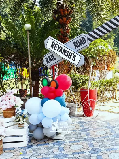I use custom signage to enhance the theme. This 'Reyansh's Rail Road' crossing sign, complete with a traffic light balloon sculpture, was a fun and personalized detail for the train party.