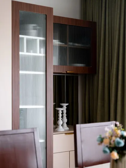 Detail of the crockery unit, featuring fluted glass doors that add texture and partially obscure the contents for a clean look. The brass handles provide a touch of understated luxury.