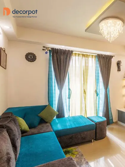 This living room uses a bold color combination of brown and teal for the sectional sofa, creating a vibrant and energetic atmosphere. A crystal chandelier adds a touch of elegance to the room.