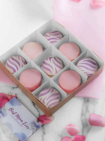 A box of my Divine Macarons, specially designed for Mother's Day. The box contains a mix of plain and striped macarons, filled with a delicious berry and white chocolate ganache.