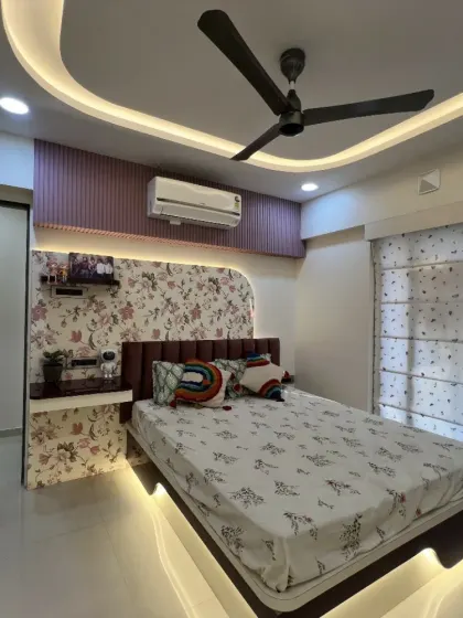 This bedroom combines floral wallpaper with a rainbow cushion and under-bed lighting, creating a cheerful and dreamy space.