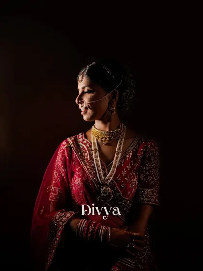 A classic, moody portrait of the bride, Divya. The dark background and soft lighting create a timeless and elegant image that focuses entirely on her.