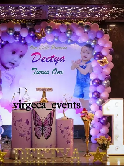 A personalized butterfly-themed first birthday with large photos of the birthday girl on the backdrop.