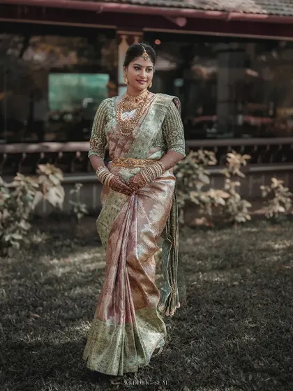 The bride in a moment of quiet contemplation, bathed in warm, natural light. Her iridescent saree and serene expression create a portrait of pure elegance.