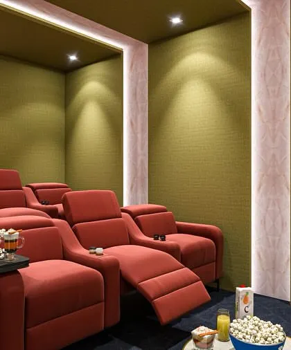 A 3D rendering of a luxury home cinema, showcasing a design with red recliners, an integrated bar area, and warm, ambient lighting.