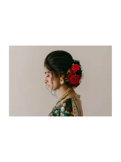 A profile shot of a bride, highlighting the beautiful red flowers in her hair. The simple background and focus on this colorful detail make for an elegant and striking portrait.