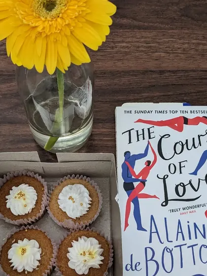 A flatlay from our "Sisters in Stories" session, featuring cupcakes, a book, and a flower. We believe in creating a beautiful and thoughtful atmosphere for our gatherings.