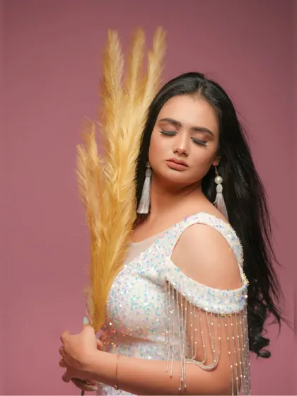 An artistic shot using pampas grass as a prop to complement the soft and glamorous feel of the white sequin dress.