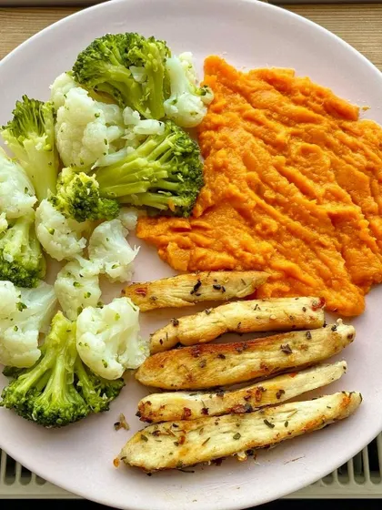 A tricolor-inspired plate with mashed sweet potato, pan-fried chicken strips, and steamed broccoli and cauliflower.