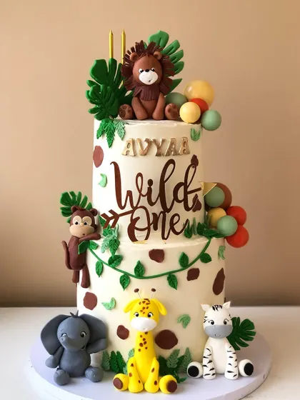 A two-tiered "Wild One" safari cake, with a mix of cute, handcrafted animals and a stylish wooden topper.