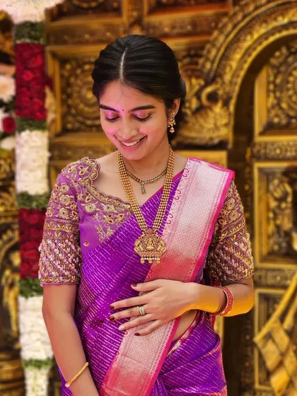 A happy and smiling client, looking beautiful in her custom-designed purple blouse and matching silk saree.
