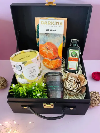 A sophisticated Diwali gift for him, this hamper includes a miniature Jägermeister, orange-flavored dark chocolate, and a scented candle in a black suitcase box.