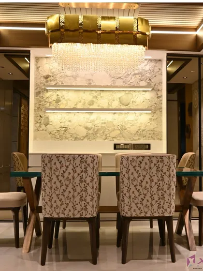 This dining area is designed for luxury, with a statement chandelier, a marble-finish accent wall, and custom-upholstered chairs. The lighting is designed to create a warm and inviting atmosphere for meals.