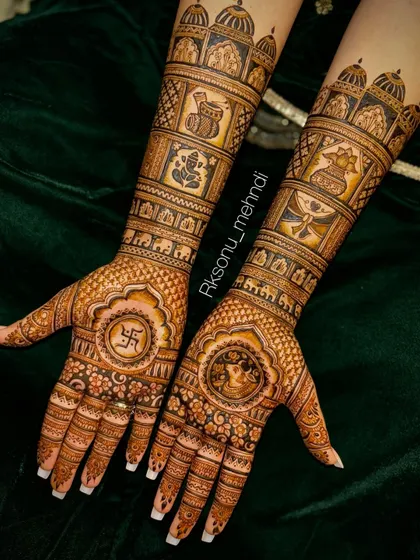 A grand bridal design filled with auspicious symbols. This full-arm mehndi includes motifs of Lord Ganesha, a swastika, kalash, and other wedding elements, framed by royal palace architecture.