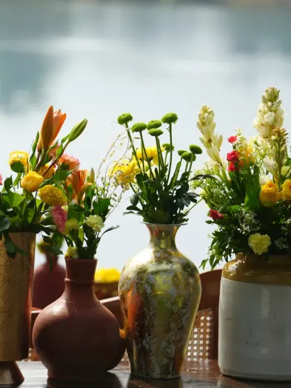 A lineup of different vases, from terracotta to ceramic and metal, each holding a unique floral arrangement, showcasing variety in detail.